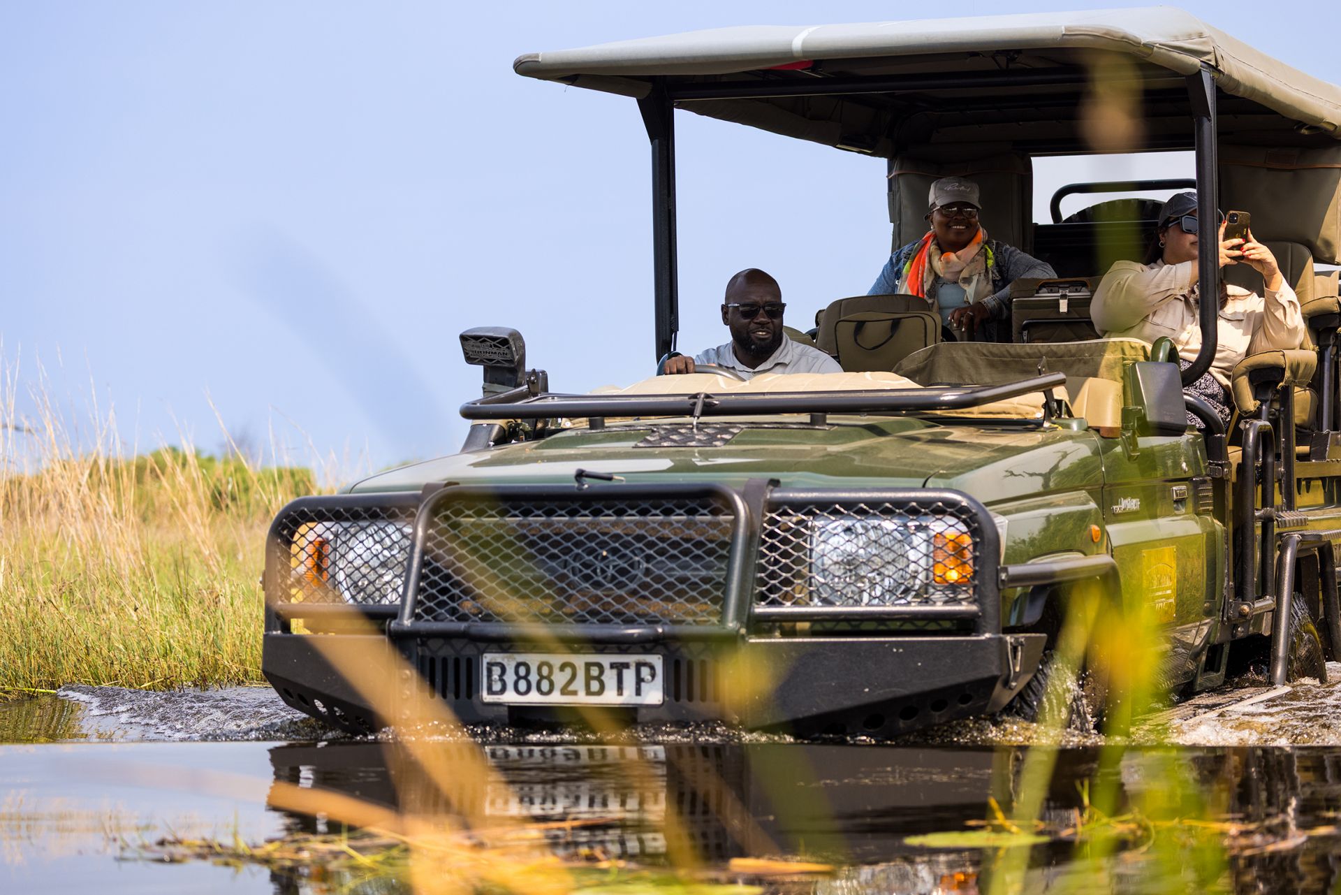 Great plains conservation duba plains camp guest in water with guide in safari vehicle