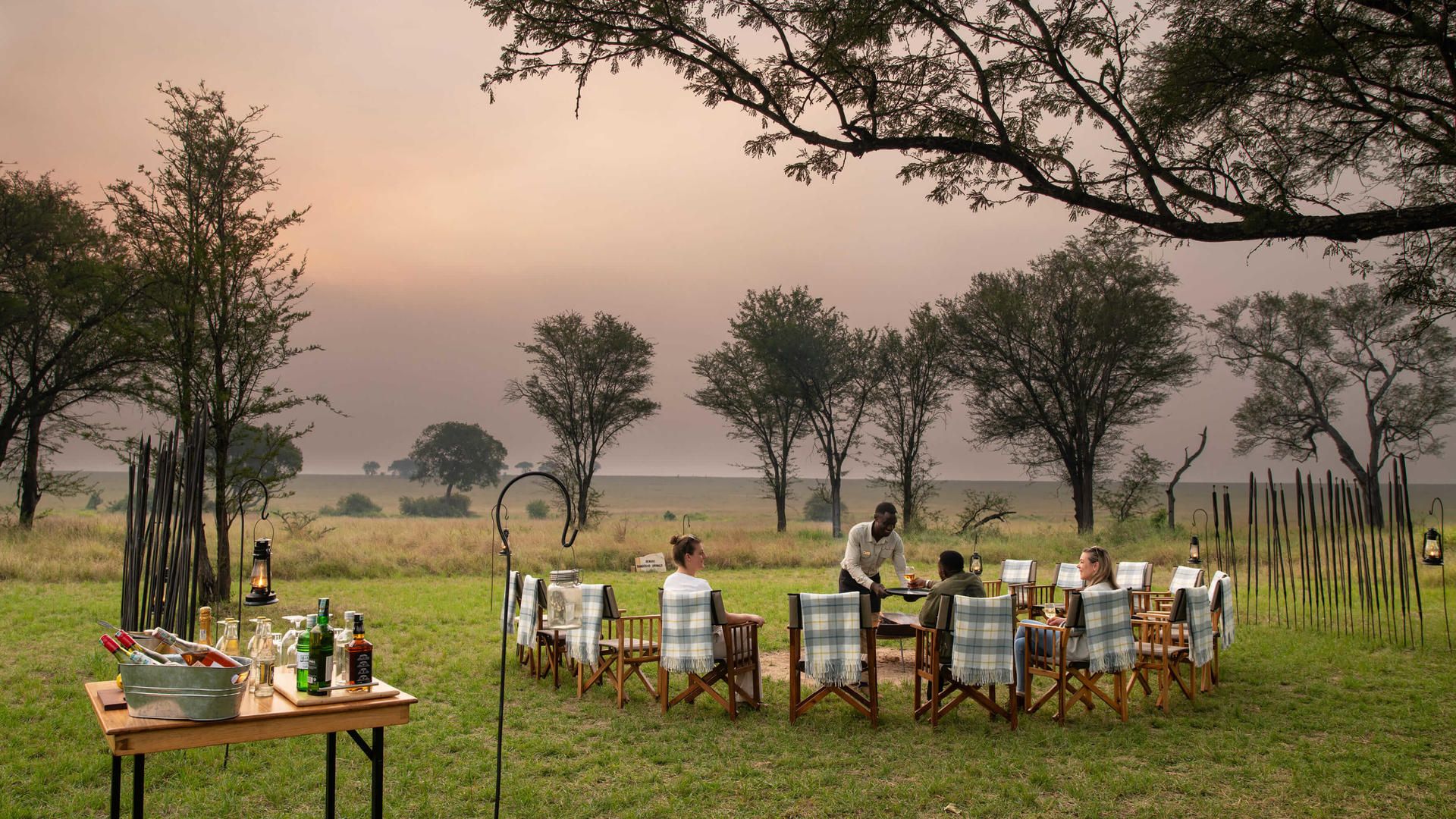 Asilia africa ubuntu migration camp guests enjoying sundowners